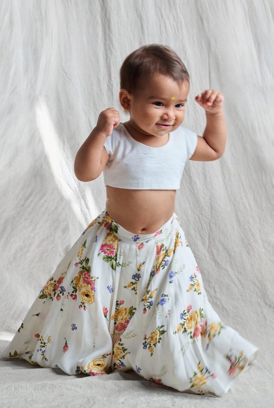 Baby in a white top and floral-print lehenga skirt by bisouNYC
